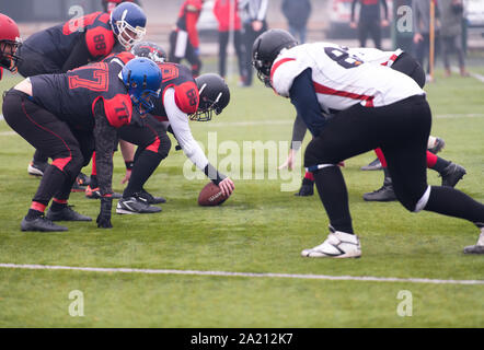 Gruppe von jungen professionellen American Football Spieler bereit während der Ausbildung übereinstimmen, der auf dem Stadion Feld beginnen Stockfoto