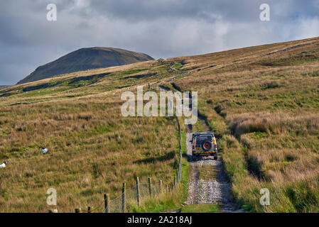 Auto auf unbefestigten Straßen in der Nähe von Helwith Brücke mit Gipfel der Pen y Gent in Abstand. Yorkshire Dales National Park, England. Stockfoto