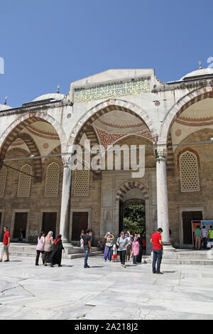 Touristen unter arch mit Kalligraphie Plakette, im Innenhof der Blauen Moschee, Fatih, Istanbul, Türkei. Stockfoto