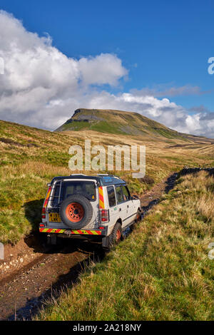 Auto auf unbefestigten Straßen in der Nähe von Helwith Brücke mit Pen y Gent darüber hinaus. Yorkshire Dales National Park, England. Stockfoto