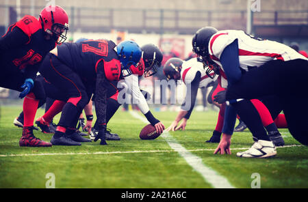 Gruppe von jungen professionellen American Football Spieler bereit während der Ausbildung übereinstimmen, der auf dem Stadion Feld beginnen Stockfoto