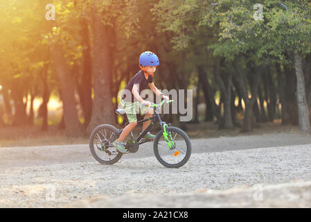 Glückliches Kind Junge von 7 Jahren Spaß im Herbst Park mit dem Fahrrad auf schönen Herbst Tag. Aktives kind Fahrradhelm tragen Stockfoto