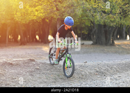 Glückliches Kind Junge von 7 Jahren Spaß im Herbst Park mit dem Fahrrad auf schönen Herbst Tag. Aktives kind Fahrradhelm tragen Stockfoto