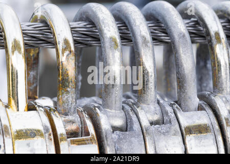 Herzförmige golden Vorhängeschlösser hängen an einem Stahldraht Nahaufnahme und Makro. Stockfoto