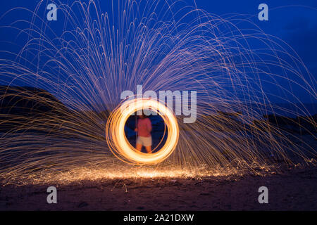 Eine Frau tun, Circular spinning Licht Malerei mit Stahlwolle bei Nacht am Strand.