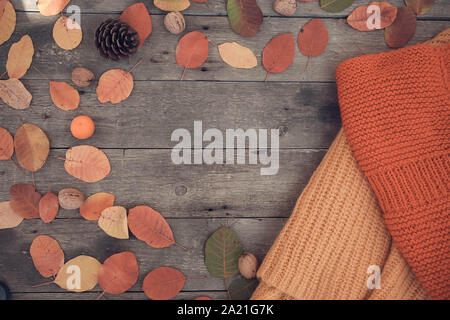 Gestrickte Sachen und Herbstlaub auf einem hölzernen Hintergrund. Ansicht von oben, Rendering, text Raum. Flach. Stockfoto