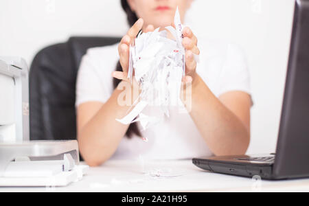 Kaukasische Mädchen Büroangestellter tränen Papier auf dem Tisch. Das Konzept von Burnout und Depression am Arbeitsplatz, Stress, chronische Müdigkeit Stockfoto