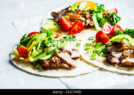 Gesunde Minibar Tortillas mit gegrilltem Huhn, Fleisch, Soße, frisches Gemüse auf hellgrauen Hintergrund, Ansicht von oben. Gesundes Essen für ein Picknick. Stockfoto