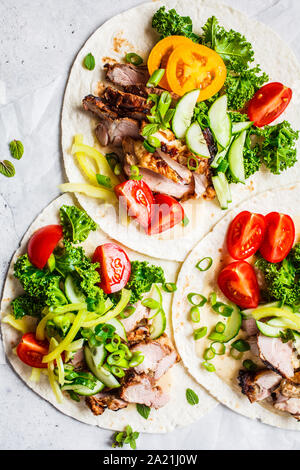 Gesunde Minibar Tortillas mit gegrilltem Huhn, Fleisch, Soße, frisches Gemüse auf hellgrauen Hintergrund, Ansicht von oben. Gesundes Essen Picknick Konzept. Stockfoto