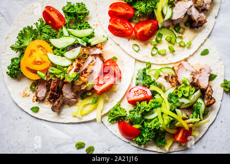 Gesunde Minibar Tortillas mit gegrilltem Huhn, Fleisch, Soße, frisches Gemüse auf hellgrauen Hintergrund, Ansicht von oben. Gesundes Essen Picknick Konzept. Stockfoto