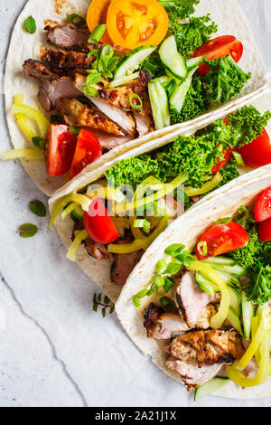 Gesunde Minibar Tortillas mit gegrilltem Huhn, Fleisch, Soße, frisches Gemüse auf hellgrauen Hintergrund, Ansicht von oben. Gesundes Essen Picknick Konzept. Stockfoto
