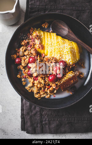 Haferflocken mit Beeren und Mango in einer schwarzen Platte gebacken. Hausgemachtes Müsli (pie bröckeln) mit Milch und Obst. Stockfoto