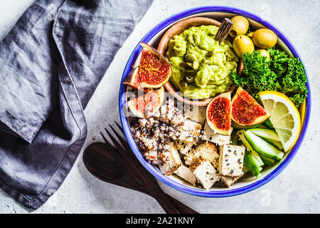 Buddha Schüssel mit Quinoa, Tofu, Kale, Feigen und Guacamole hummus in eine weiße Platte. Stockfoto