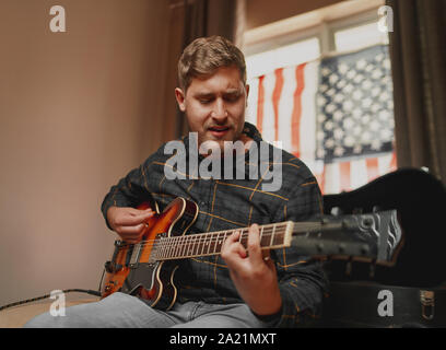Stattlichen amerikanischen Mann spielt Gitarre und singt mit Leidenschaft zu Hause Stockfoto