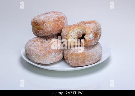 Ein Stapel von Gezuckertem Marmelade, Krapfen auf einer weißen Platte. Man hat einen Bissen aus. Stockfoto