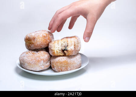 Einen Teller mit Zuckerwasser jam Krapfen mit einer Hand erreichen für Sie. Stockfoto