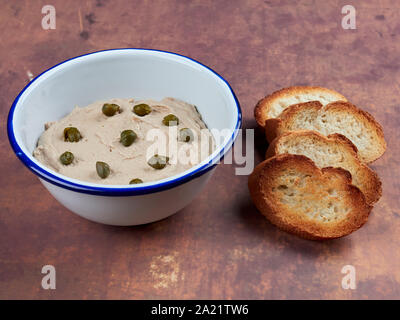Geräucherter Thunfisch Butter dekoriert mit mit Kapern, mit gerösteten Scheiben Baguette serviert. Stockfoto