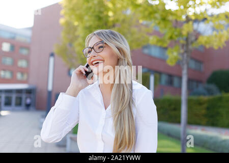 Glückliche junge Kaukasier blond Geschäftsfrau in Park Stockfoto