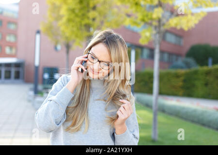 Blonde junge Freiberufler Frau Aufruf im Park im Herbst Stockfoto