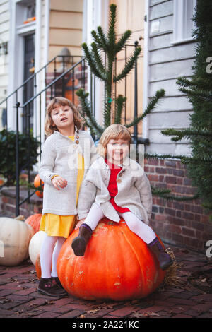 Zwei Mädchen sitzen auf die grosse orange Kürbis in der Altstadt von Alexandria, Virginia Stockfoto