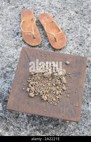 Abgenutzte hippy Flipflops &square mit Masse an der Betonoberfläche. Metapher flachen Erde Theorie, Flat earthers, Verschwörungstheorien, flachen Erde Beweise. Stockfoto