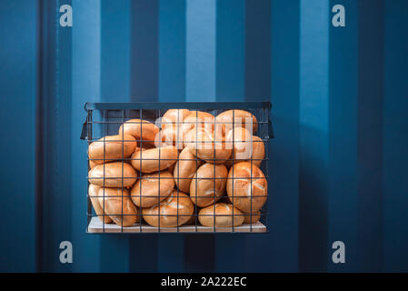 Leckere Brötchen im Korb auf einem blauen Wand. Frisch gebackene Brötchen auf blauem Hintergrund. Bäckerei Zusammenhang mit Kopieren. Straße Brötchen. Stockfoto