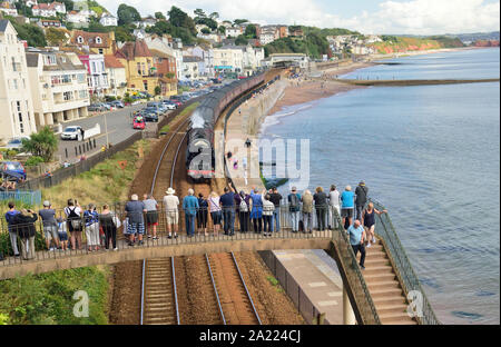 Menschen auf einer Fußgängerbrücke beobachten die Eisenbahntour des Königlichen Herzogtums durch Dawlish, die von der LMS Pacific No. 6233 'Herzogin von Sutherland' gezogen wird. 01.09.2019. Stockfoto