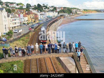 Menschen auf einer Fußgängerbrücke beobachten die Eisenbahntour des Königlichen Herzogtums durch Dawlish, die von der LMS Pacific No. 6233 'Herzogin von Sutherland' gezogen wird. 01.09.2019. Stockfoto