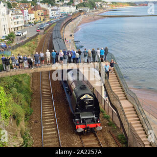 Menschen auf einer Fußgängerbrücke beobachten die Eisenbahntour des Königlichen Herzogtums durch Dawlish, die von der LMS Pacific No. 6233 'Herzogin von Sutherland' gezogen wird. 01.09.2019. Stockfoto