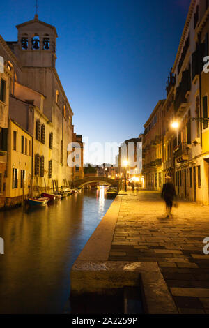 Frau geht alleine Dow eine Venedig Canal Street in der Dämmerung mit Straßenbeleuchtung Stockfoto