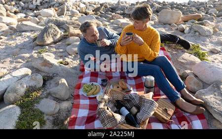 Paar mit einem Picknick am Meer Stockfoto