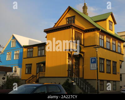 Skolavoerdustigur Street im Zentrum von Reykjavik mit einem auffallend gelben Haus und ein helles blaues Gebäude nebenan. Stockfoto