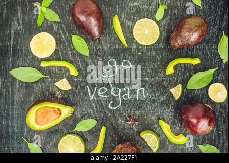 Vegan Konzept mit Schriftzug gehen. Auswahl von frischem Grün Bio Gemüse Linsen auf dunklem Hintergrund. Veganes essen Konzept Stockfoto