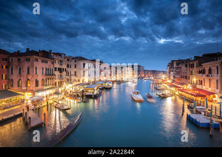 Abend des Canale Grande Venedig mit einem dramatischen Himmel und lebhaft bunten Bars und Restaurants Stockfoto