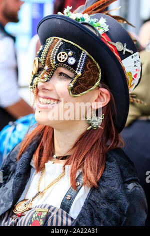 Piraten Tag, Hastings. Schönen Kaukasischen junge Frau mit verzierten Gesichtsmaske über einem Auge gekleidet wie Steam Punk Pirate. Mit Blick auf die Zukunft und Lachen. Stockfoto