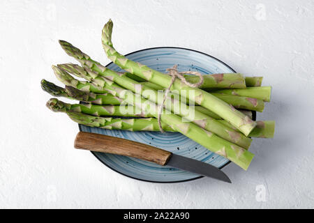 Grüner Spargel sprießen auf blauen Platte auf weißer Tisch. Essen Fotografie Stockfoto