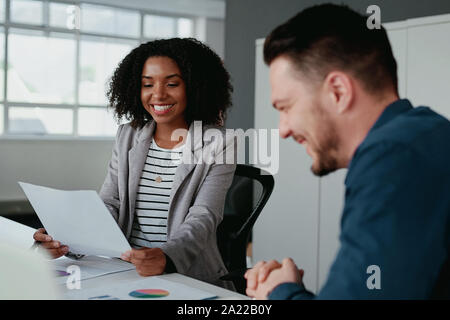 Zwei verschiedene junge freundliche Geschäft Leute in formale Diskussion über das Projekt am Arbeitsplatz Stockfoto