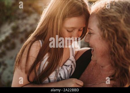 Seitenansicht der Mutter und des rothaarigen elementare Alter Tochter bei Sonnenuntergang Stockfoto