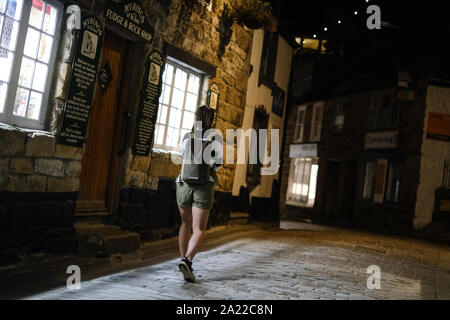 Frau alleine zu Fuß entlang Fore Street in St Ives, Cornwall bei Nacht Stockfoto