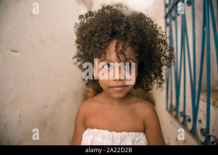 Schöne afro-brasilianischen Mädchen mit lockigem Haar und weißem Kleid, lächeln Stockfoto