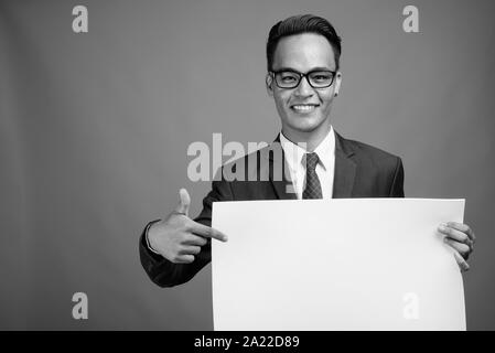 Junge hübscher indischer Geschäftsmann gegen grauer Hintergrund Stockfoto