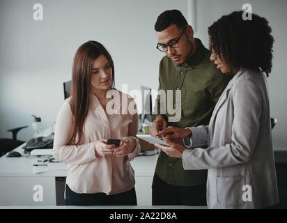 Gruppe von Multiethnischen jungen konzentriert, Geschäftsleute, die sich mit digitalen Tablet am Arbeitsplatz Stockfoto