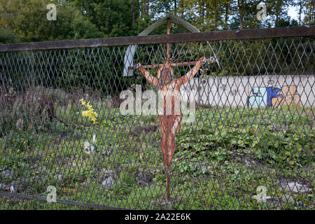 Ein Blech Jesus Kruzifix (eine populäre lokale Kopie von einem historischen Rutherian Kirche) außerhalb einer verlassenen Industriegebäude am Stadtrand von Jaworki, am 20. September 2019, in der Nähe von Szczawnica, Malopolska, Polen. Das Dorf eines florierenden Rutherian Gemeinschaft war einmal in der Nähe Biala Woda wo über 100 Farmen wurden - die Reste davon sind noch heute zu sehen. Ein hölzernes Kreuz mit Christus Schneiden von Blech überlebte der Kultur. Ähnlich wie Kreuze und Kapellen kann in der Umgangssprache der Weißen Wasser in der Rumänisch, Ukrainisch oder Ostslowakei Karpaten gefunden werden. Stockfoto