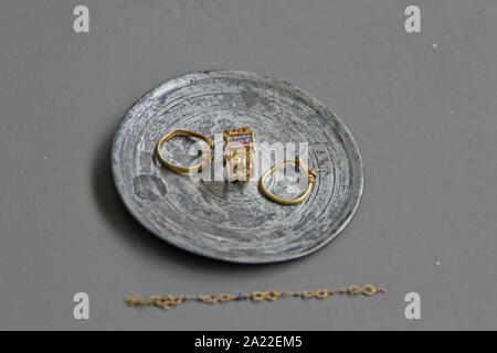 Goldene Ringe und Ohrringe angezeigt auf Platte mit goldenes Armband Kette auf der Seite, den Nationalen Archäologischen Museum Djerdap, Kladovo, Serbien. Stockfoto