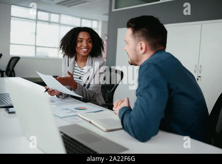 Ein afroamerikanischer junge Frau zu erklären, kaukasischen Kollegen neue Idee und Plan für Business Improvement in Office Stockfoto