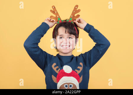 Frohe Weihnachten. Kind in einem Rudolph Rentier Weihnachten Kostüm auf gelbem Hintergrund Stockfoto