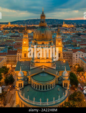 Die St. Stephan Basilika. in Budapest, Ungarn. Sonnenuntergang mit Wolken, Budaer Burg und der Fischerhochburg im Hintergrund Stockfoto