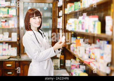 Perfekte Medikation. Schuss eine junge schöne Apotheker auf der suche nach ein bestelltes Medikament auf einem Regal in der Apotheke. Stockfoto