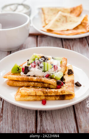 Dreieck gerollte Pfannkuchen mit Sahne, Schokolade, Banane, Kiwi, Granatapfel Stockfoto