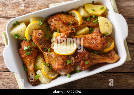 Hot würzigen Hähnchenkeulen mit Zitrone und gebackene Kartoffeln mit Knoblauch Sauce close-up in einer Auflaufform auf den Tisch. horizontal oben Ansicht von oben Stockfoto